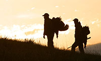 Two turkey hunters on a mountain at sunset